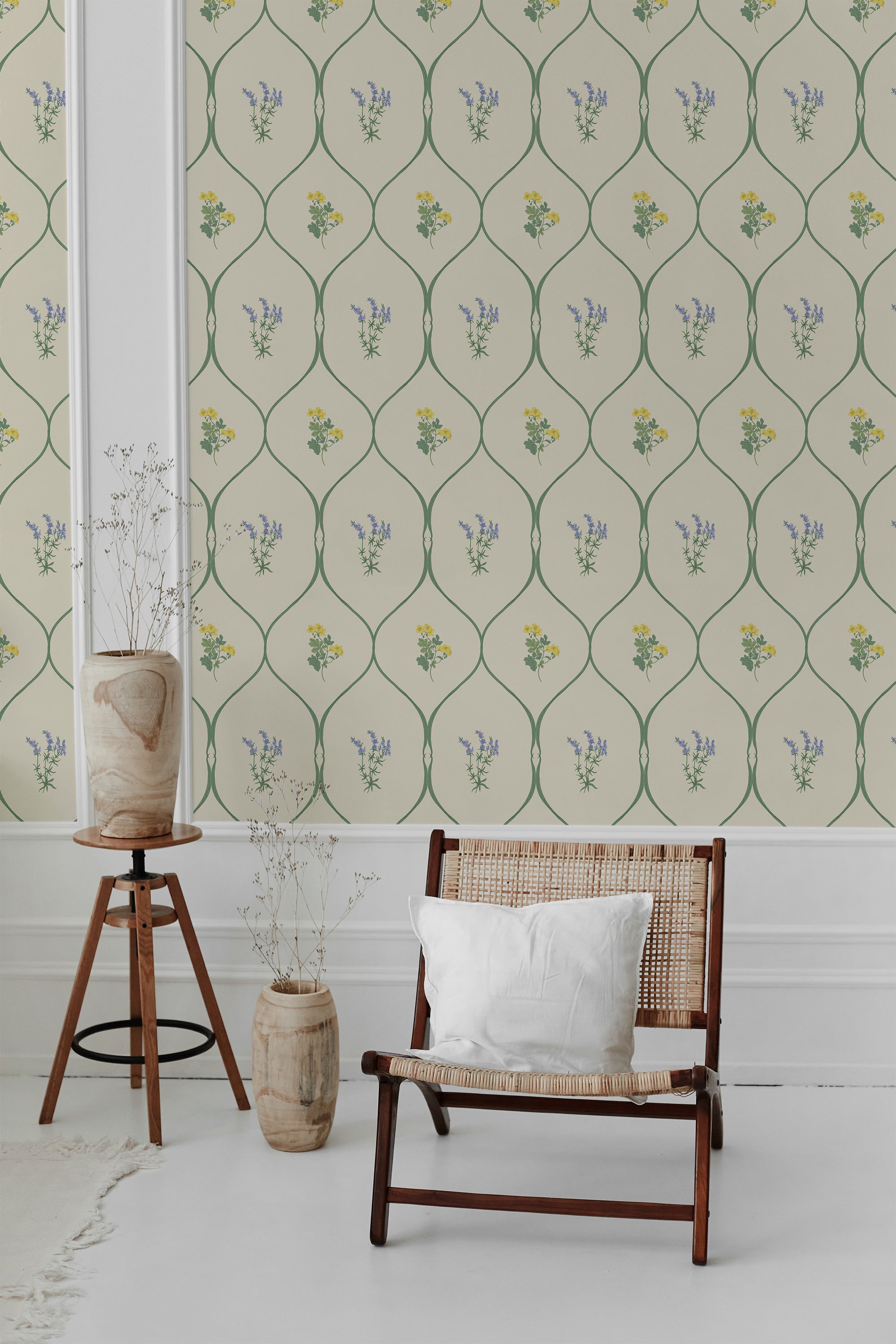 This image shows a wallpaper design with a delicate pattern of green vines encircling small clusters of yellow and blue flowers on a light beige background, giving the room a vintage, traditional wallpaper.