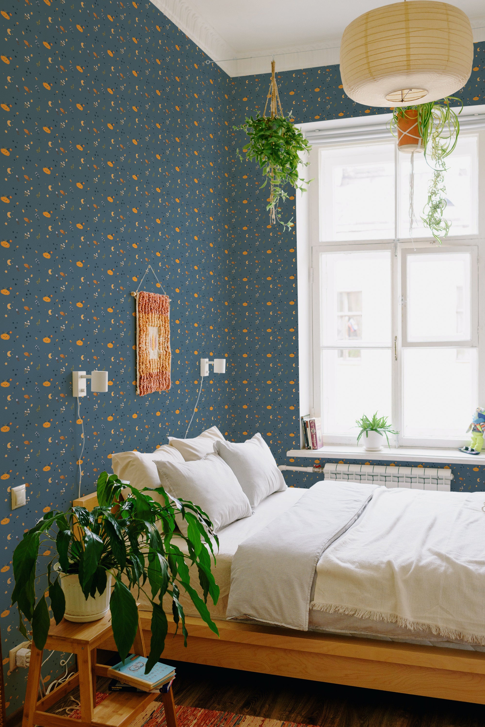 A bedroom with blue wallpaper adorned with small orange pumpkins and yellow crescent moons, giving a whimsical Halloween pumpkin patch vibe, traditional wallpaper.