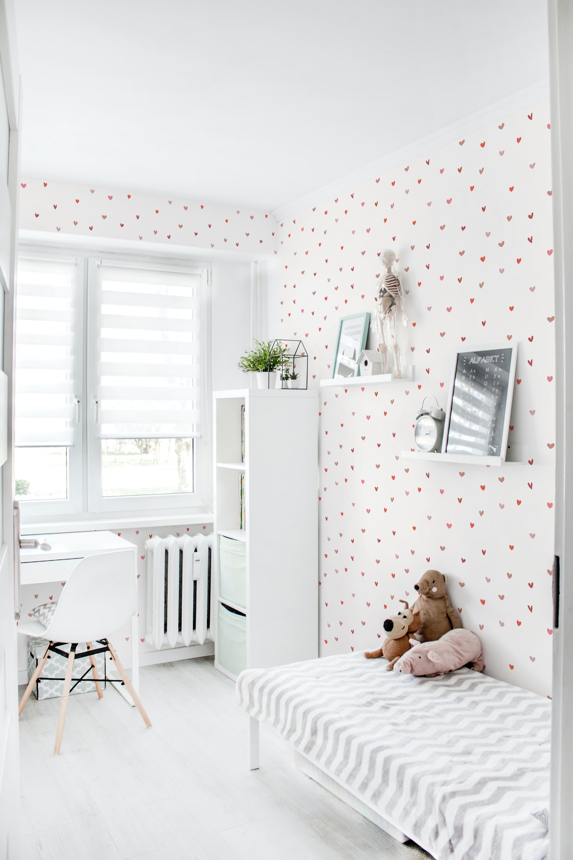A bright room with walls covered in white traditional wallpaper patterned with small red hearts and subtle gray dots.