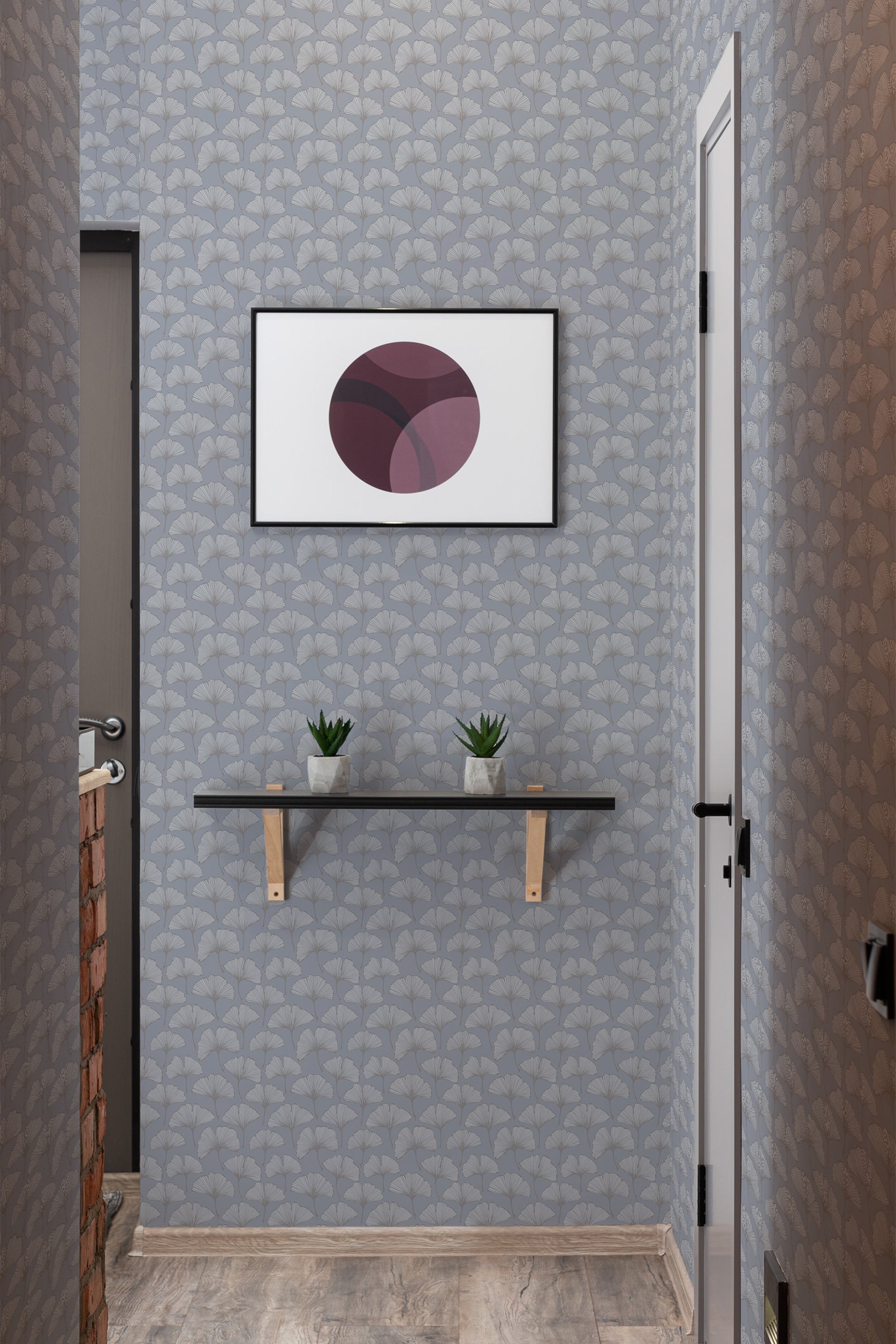 A room with gray ginkgo leaf patterned wallpaper, complemented by a framed abstract artwork, wooden shelf with green plants, and a touch of exposed brickwork. Traditional wallpaper.