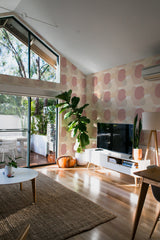 A bright room with a wall covered in simple boho-style geometric wallpaper with large, spaced circles in muted tones, complementing the modern decor and natural light, traditional wallpaper.