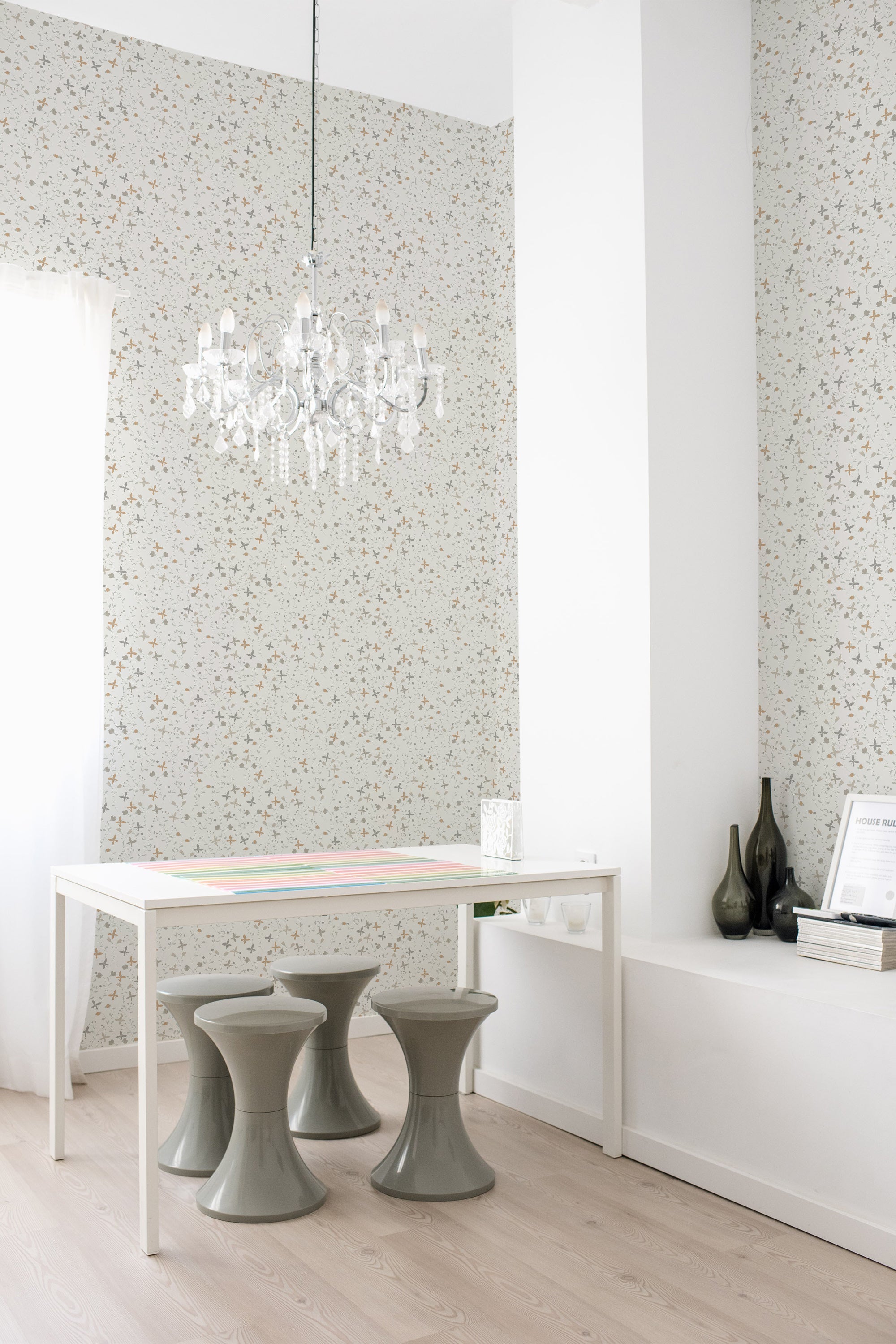 A room with a wall covered in Spring cottage-style wallpaper with small, delicate floral patterns in subtle colors, accented by a white chandelier and modern furniture, embodying a traditional wallpaper.