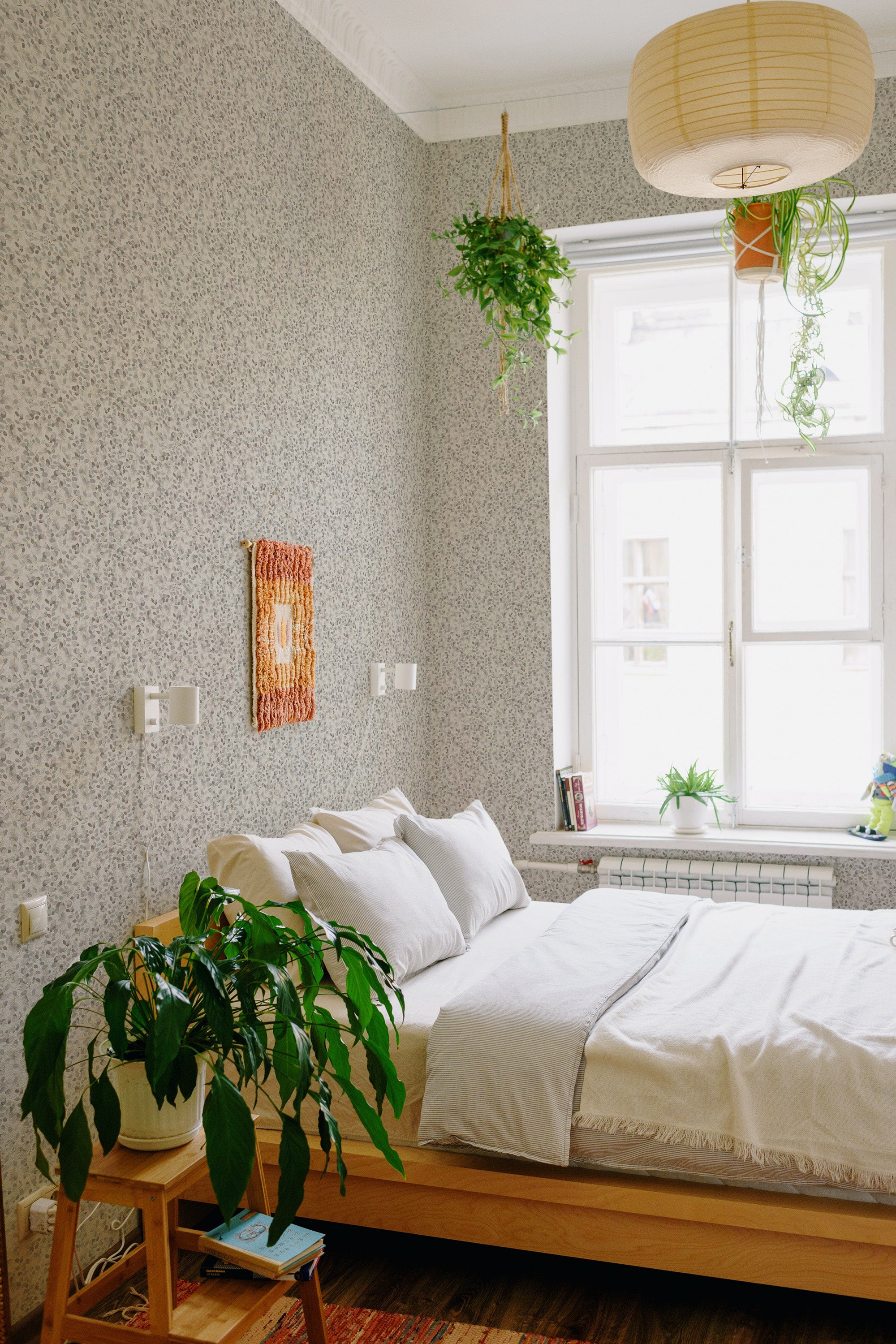 A cozy bedroom with walls adorned in Aesthetic spring leaves wallpaper, a design incorporating delicate foliage patterns, complemented by indoor plants, traditional wallpaper.