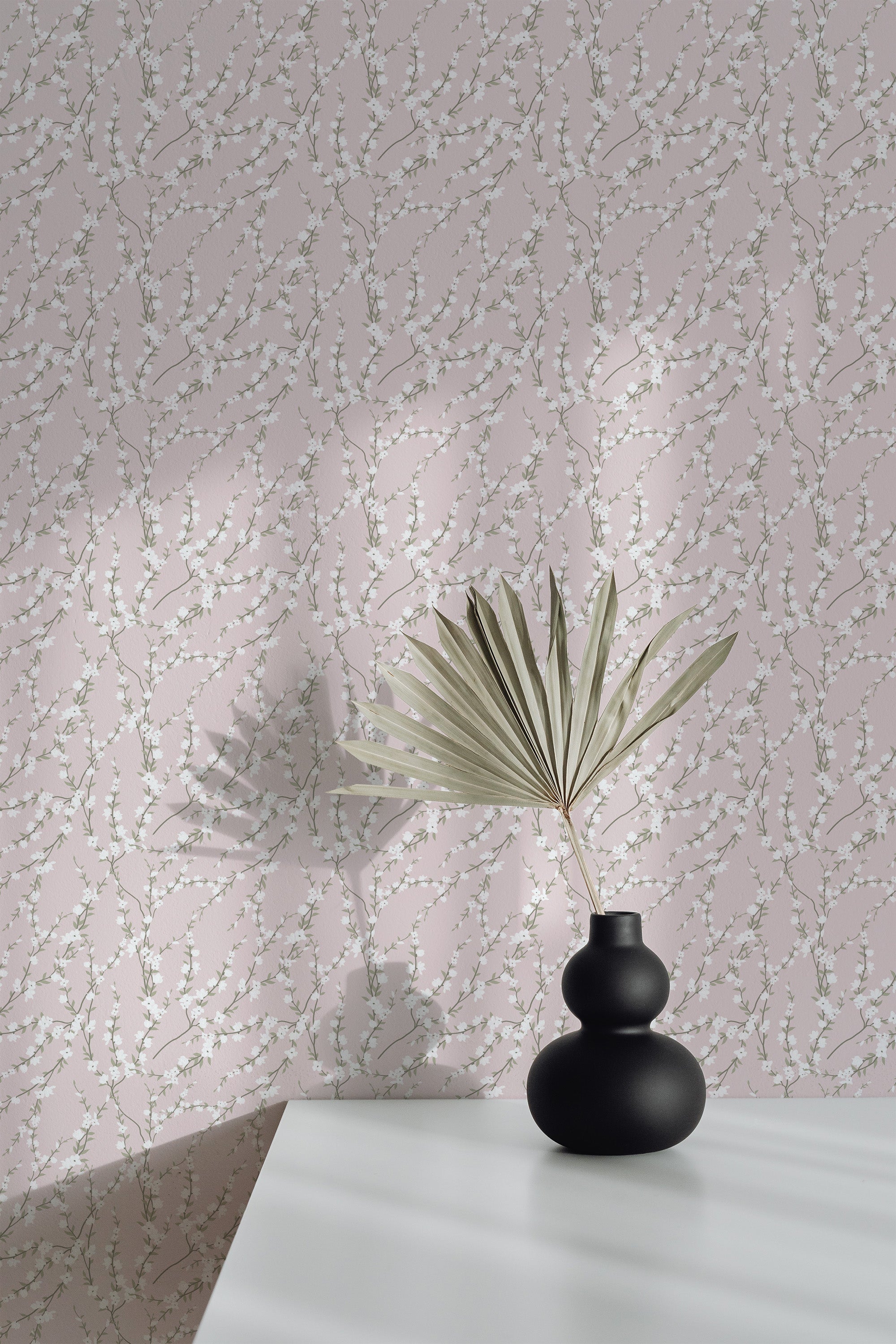 Self-adhesive wallpaper with a blooming spring tree pattern, delicate branches, and blossoms on a pale background, complemented by a potted plant's silhouette.