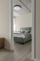 A bedroom with light-colored Cute Bunnies wallpaper on the wall behind a green upholstered bed, giving the space a soft and whimsical ambiance, traditional wallpaper.