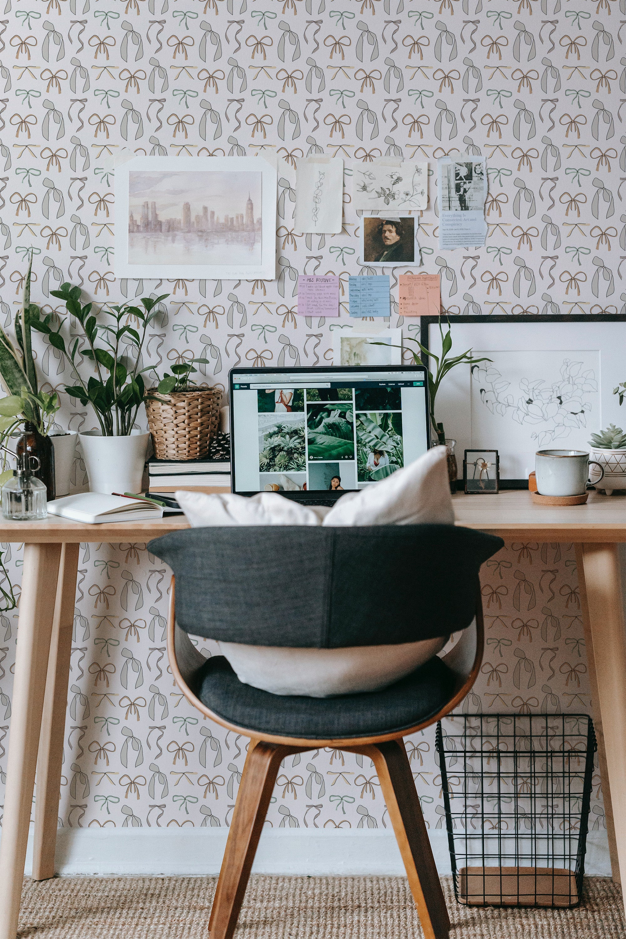 Self-adhesive Vintage bow wallpaper with a pattern of interconnected bows and leaves in a soft color scheme, accentuating a cozy workspace with plants and a computer.