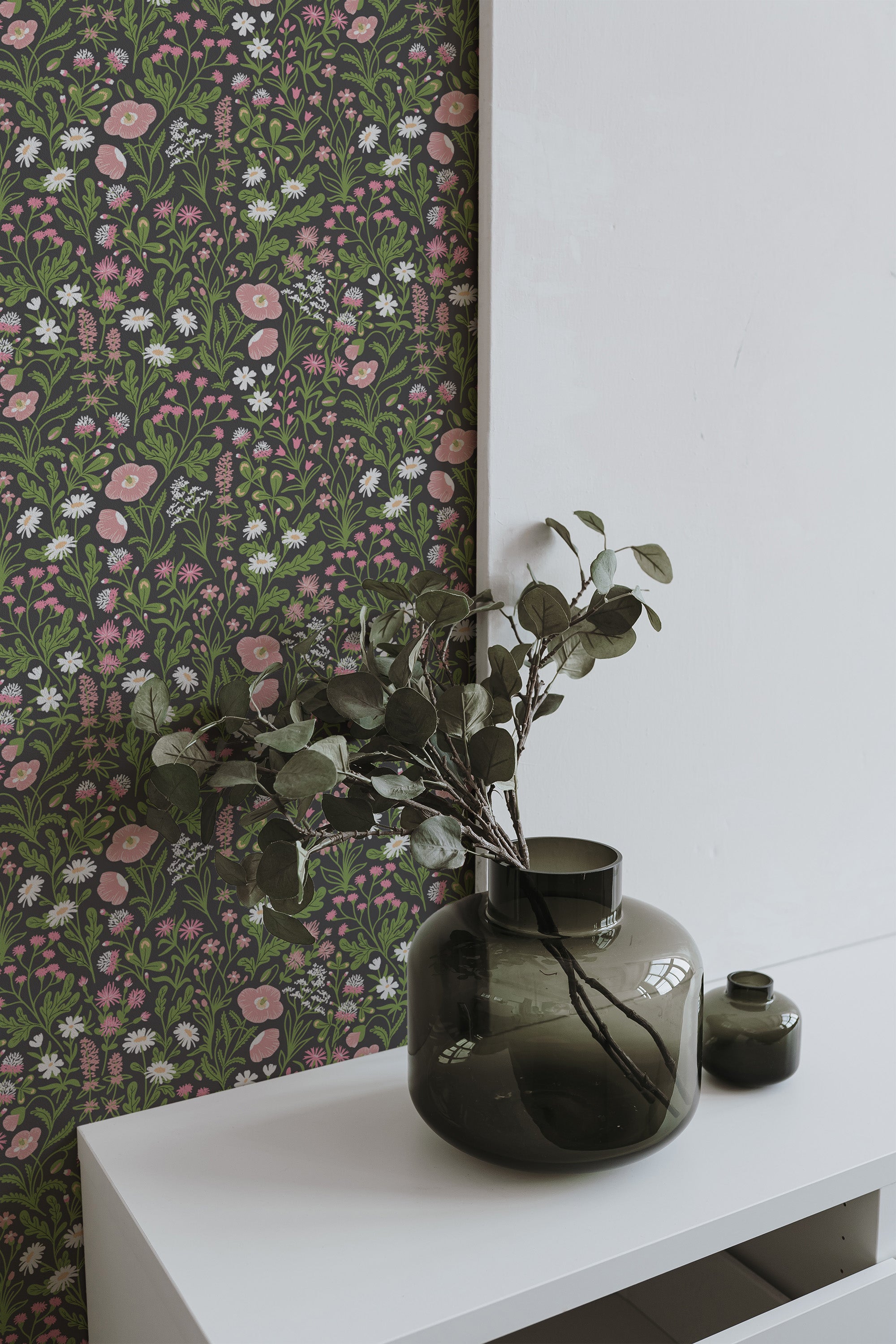 Self-adhesive brown aesthetic floral wallpaper with a pattern of pink, green, and blooms on a dark background, accentuated by a green vase with foliage on a white shelf.