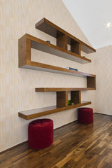 A room with beige and white striped wallpaper adding a subtle pattern to the wall, complemented by modern wooden shelving and two red ottomans, evoking a sense of neutral elegance in a traditional wallpaper style.