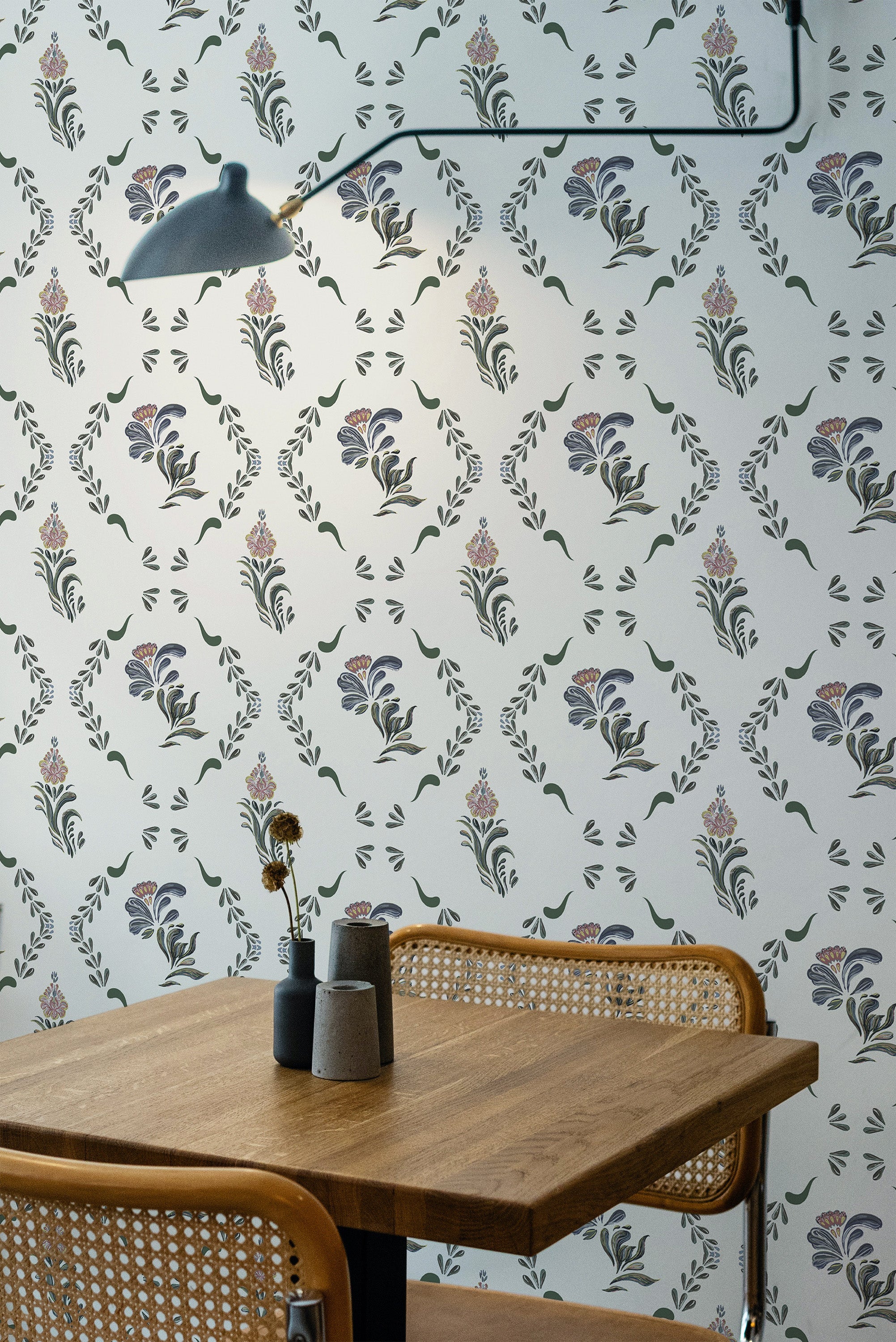Self-adhesive Country floral wallpaper with purple and blue flowers with green leaves on a pale background, covering a room with a wooden table and chairs.