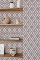 Self-adhesive wallpaper with a repeating geometric quatrefoil pattern in gray and white tones, flanked by wooden shelves with assorted decorative items.