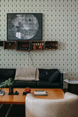 A room with green wallpaper adorned with a repeated elegant and symmetrical motif, providing a sophisticated and traditional wallpaper aesthetic.