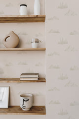 Self-adhesive wallpaper with a minimalist mountain pattern in light hues on a neutral background, accentuated by wooden shelves holding decorative items.