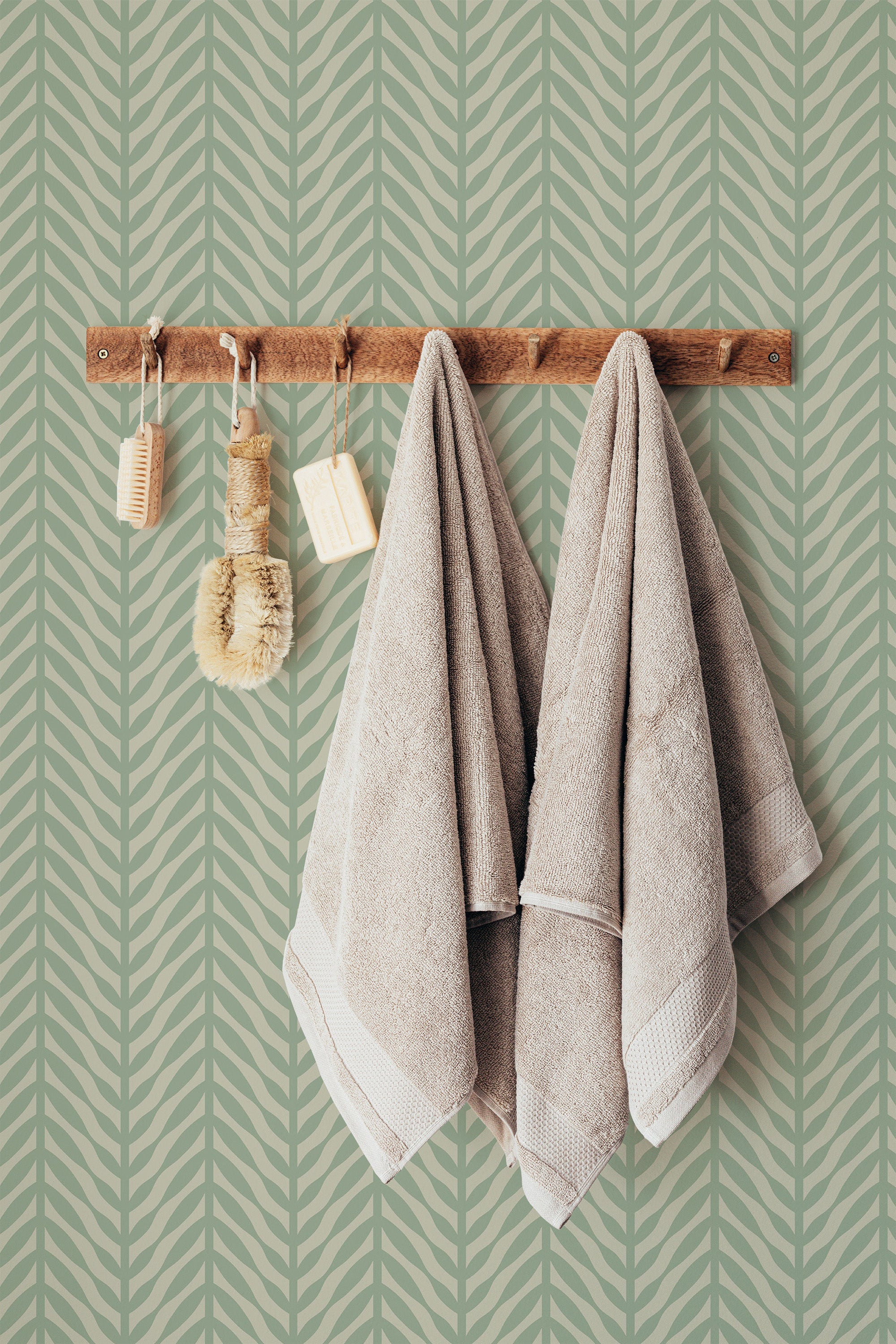 Self-adhesive green herringbone pattern wallpaper with towels hanging on a wooden rack.