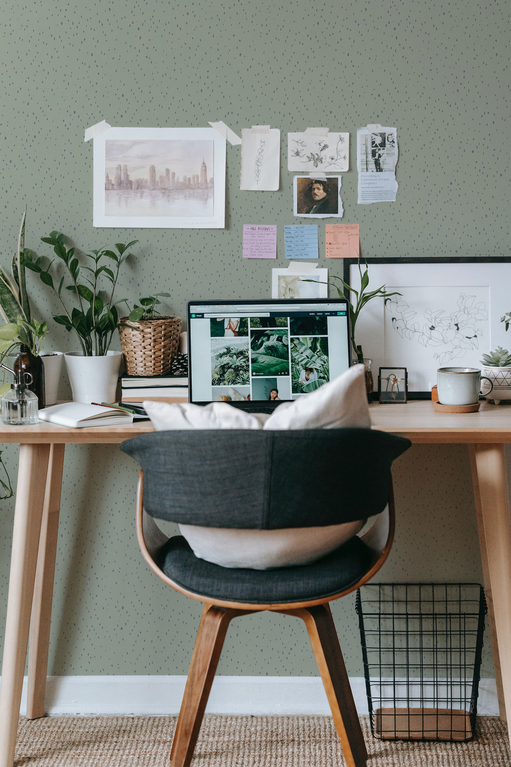 Self-adhesive wallpaper with a pattern of green and gray spots on a room wall, complemented by a desk and chair set against it.