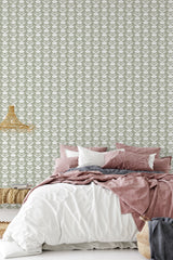 A bedroom with a wall covered in Lined Flower patterned wallpaper with rows of stylized floral motifs in soft tones, behind a bed dressed in pink and white bedding, traditional wallpaper.