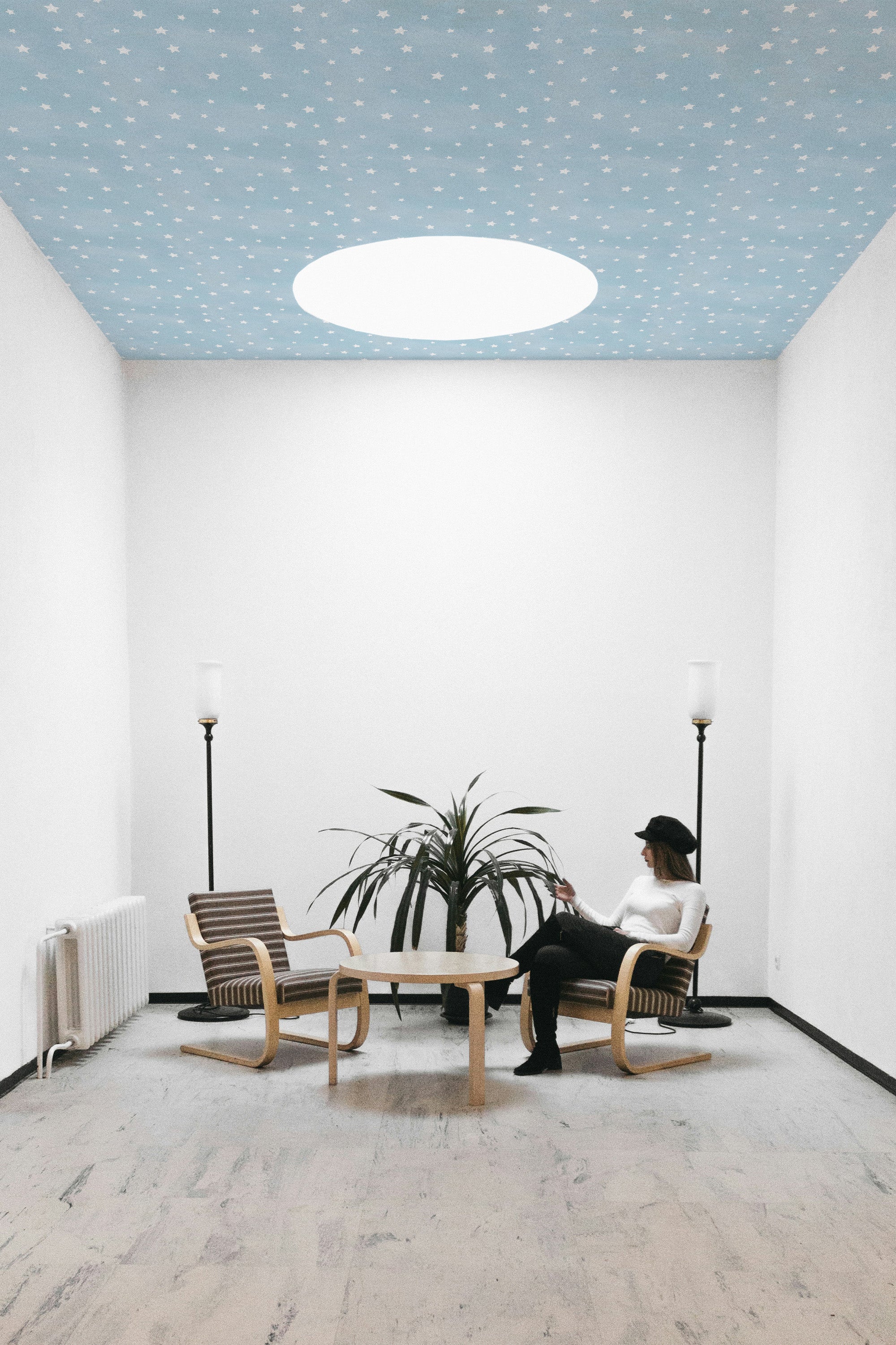 Person sitting on a chair in a room with a blue and white star ceiling.