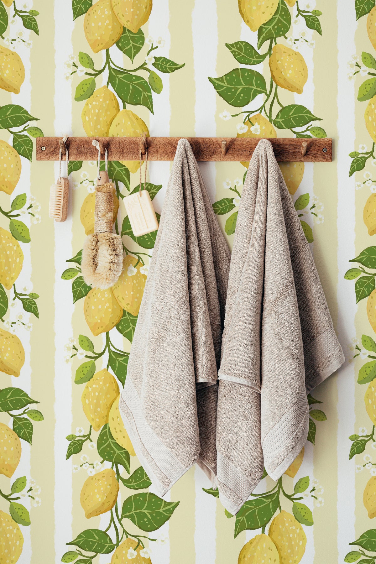 Zesty Lemon Vines pre-pasted wallpaper in a bathroom, featuring yellow lemons and green leaves over a soft striped background.