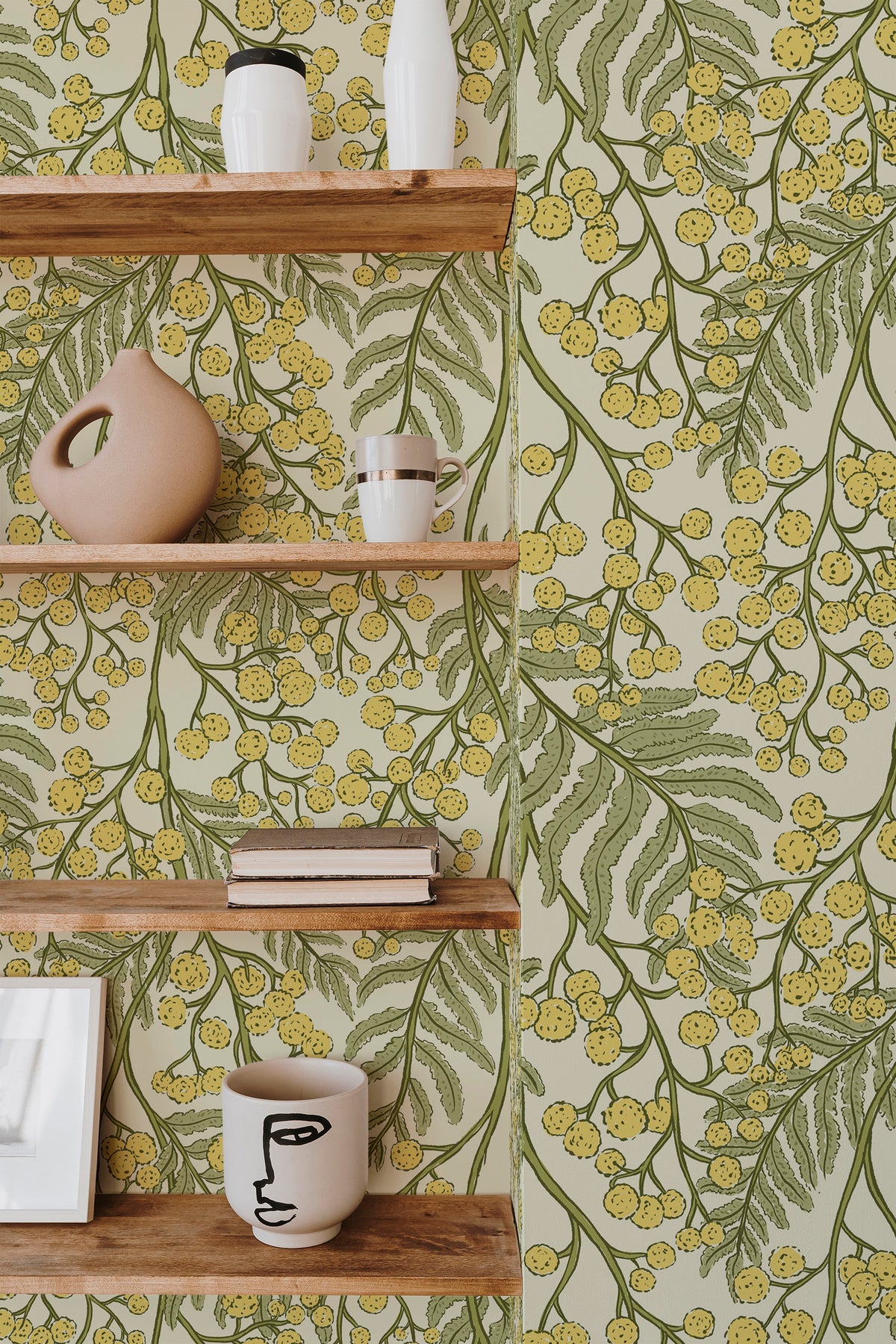 Airy Mimosa Sprigs peel and stick wallpaper on an interior wall, with green foliage and soft yellow mimosa blooms on a pale background.