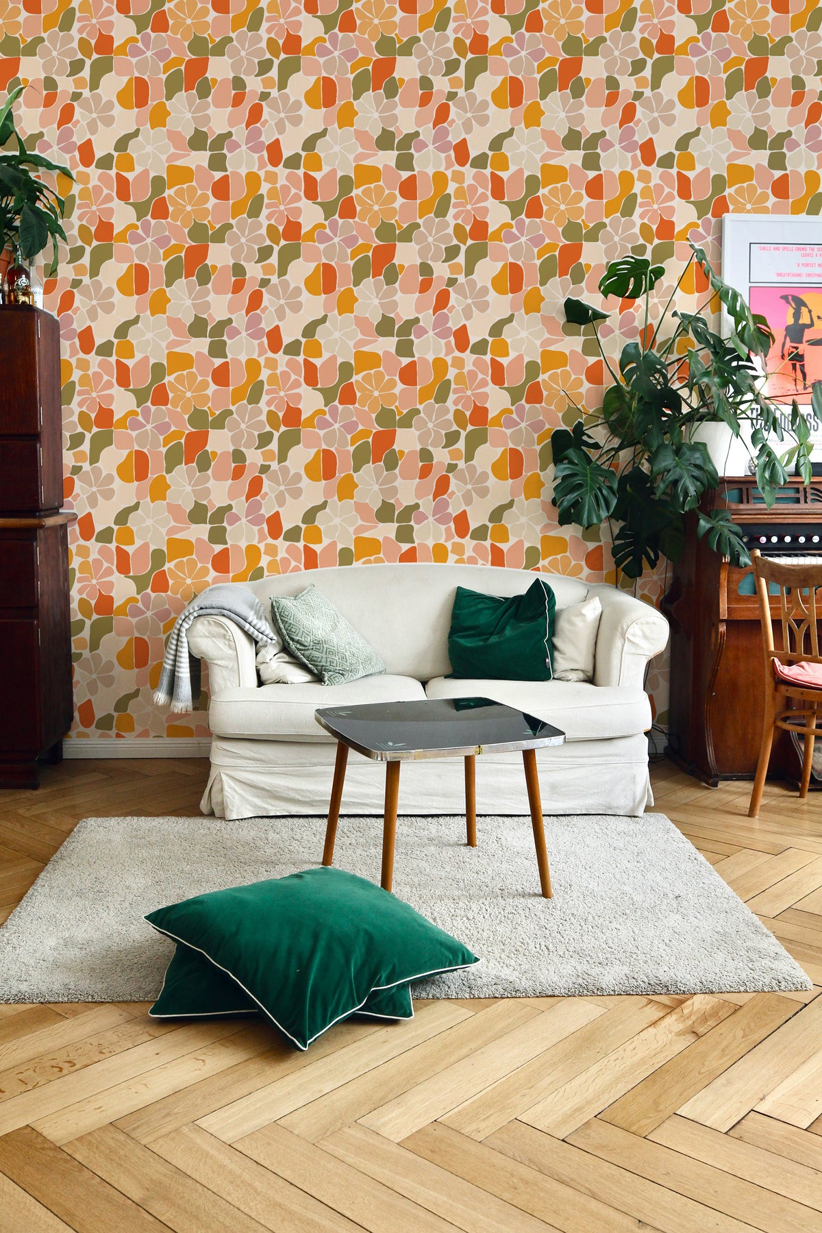 Mosaic Flora peel-and-stick wallpaper on a living room wall, floral mosaic in peach, orange, and green.