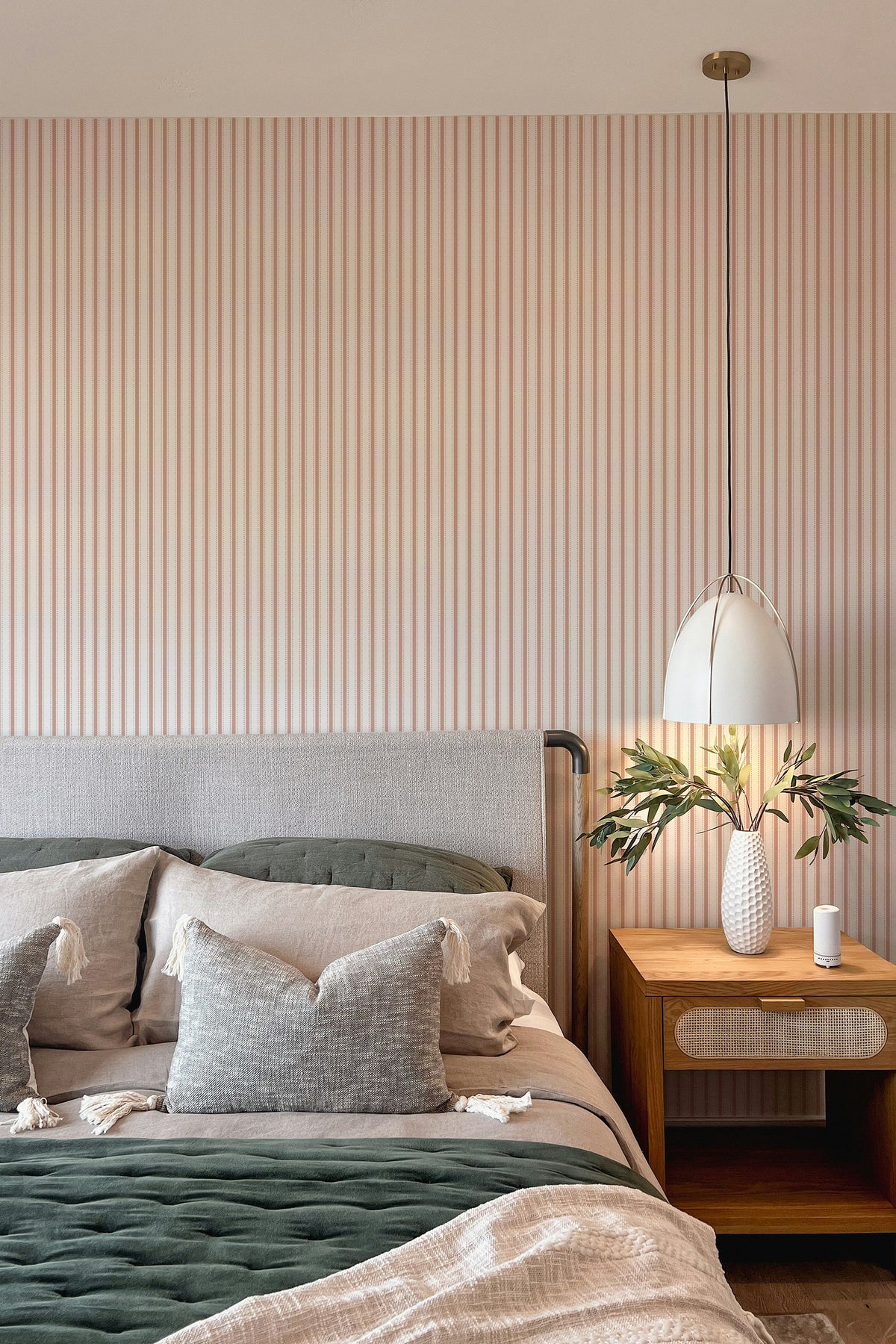 Delicate Pinstripe peel and stick wallpaper in a bedroom, shown as a full wall of orange and white vertical stripes.