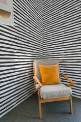 Black and white wallpaper with uneven, horizontal stripes running across the wall. The lines vary slightly in thickness and alignment, creating a playful yet orderly pattern, covering the entire wall of the room. The overall aesthetic gives a bold, dynamic look, balanced by the classic simplicity of lines, adding a modern touch to the otherwise traditional wallpaper.