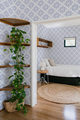 An image of a room with blue and white patterned wallpaper arranged in a repeating geometric tile design with floral motifs, giving the space a classic and elegant look. The walls are adorned with traditional wallpaper.