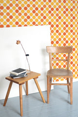 Self-adhesive wallpaper with a playful pattern of yellow and orange dots in a repeating geometric arrangement, adding warmth and a retro vibe to the room.