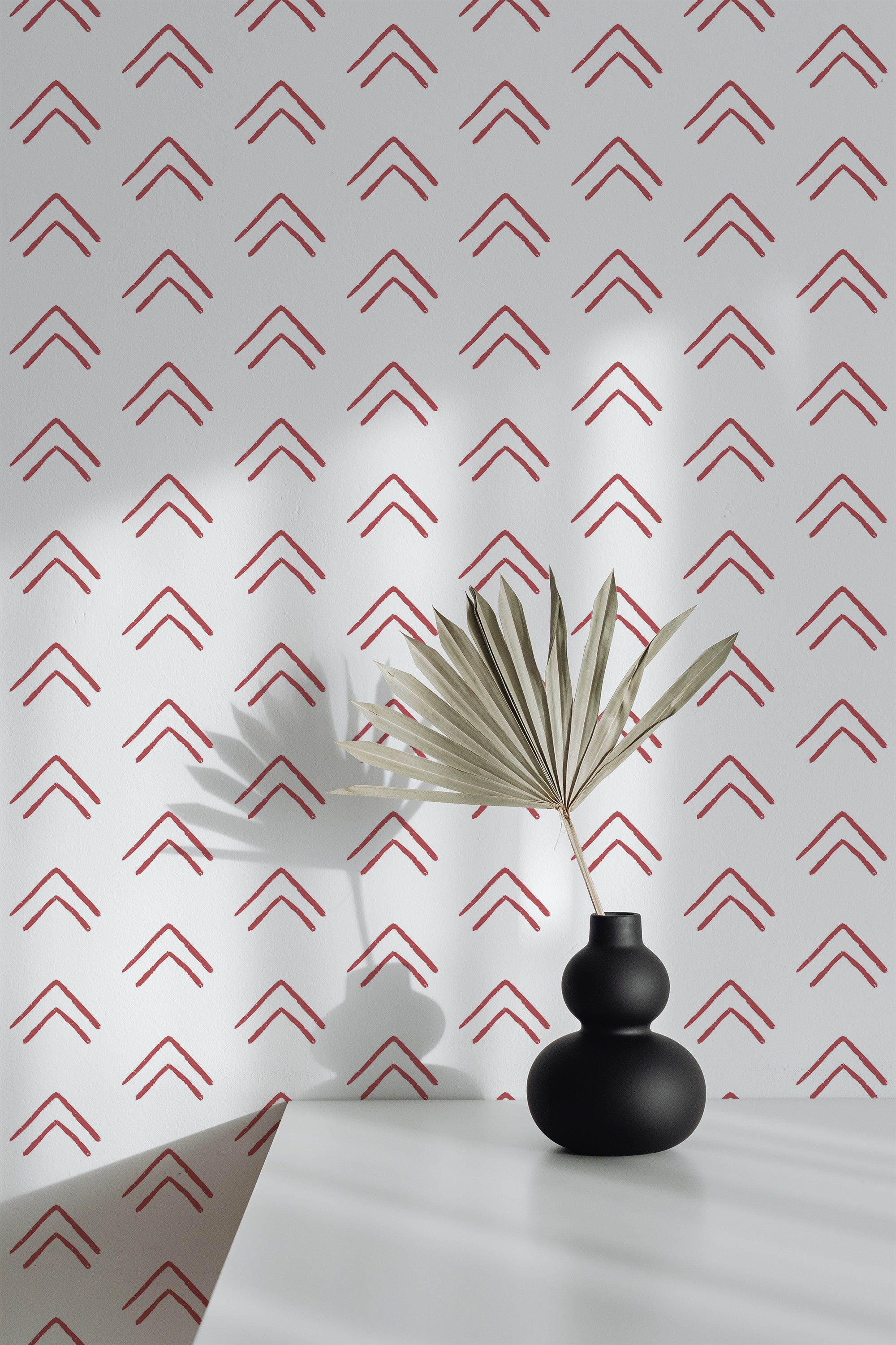 Self-adhesive wallpaper with a minimalistic design of repetitive, bold, upward-facing red chevron patterns on a light background.