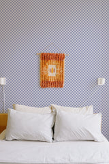 Self-adhesive geometric floral wallpaper with a repeating pattern of small white flowers against a deep blue background, adding a subtle yet elegant design to the wall above a bed with white pillows and soft bedding.