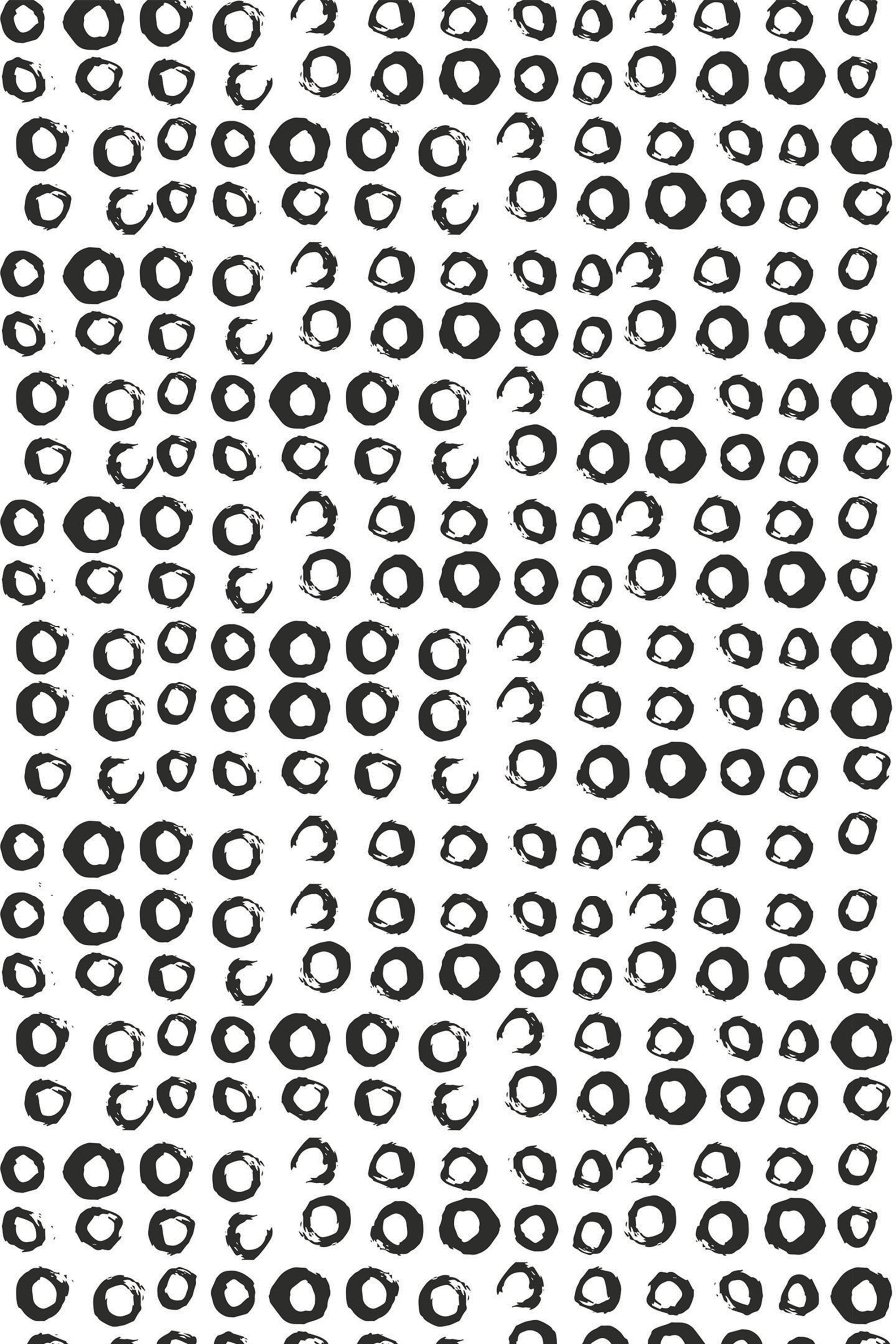 A repeating black and white pattern made up of hand-drawn, irregular small circles scattered randomly on a clean white background. Peel and stick removable wallpaper.
