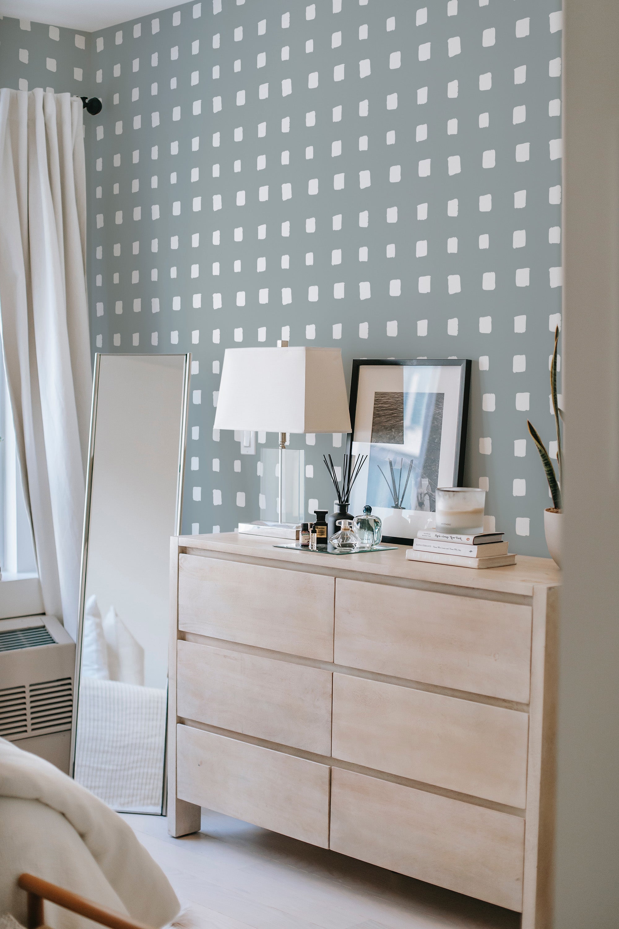 A gray wall covered with white square block patterns in a simple and modern grid layout, complementing the room's decor, traditional wallpaper.