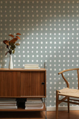 Self-adhesive wallpaper with a block pattern of evenly spaced, small square shapes on a soft gray-blue background.