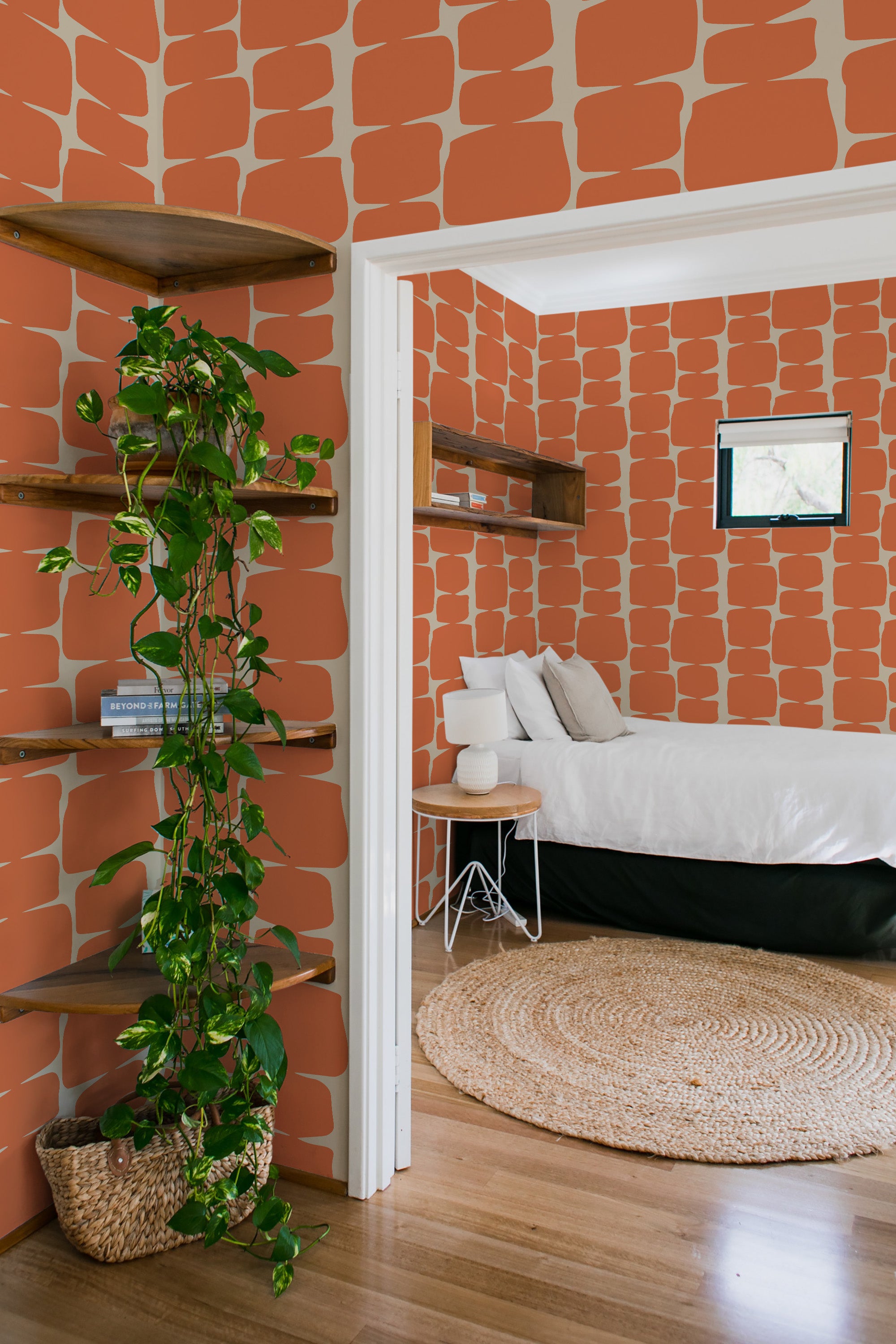 A room with orange wallpaper covered in abstract, irregularly shaped blocks that have a mid-century modern vibe, giving the space a vintage, warm aesthetic. Traditional wallpaper.