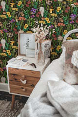Self-adhesive mushroom garden wallpaper with colorful mushrooms, yellow flowers, green foliage, and whimsical nature-inspired elements on a dark background behind a bedside table.