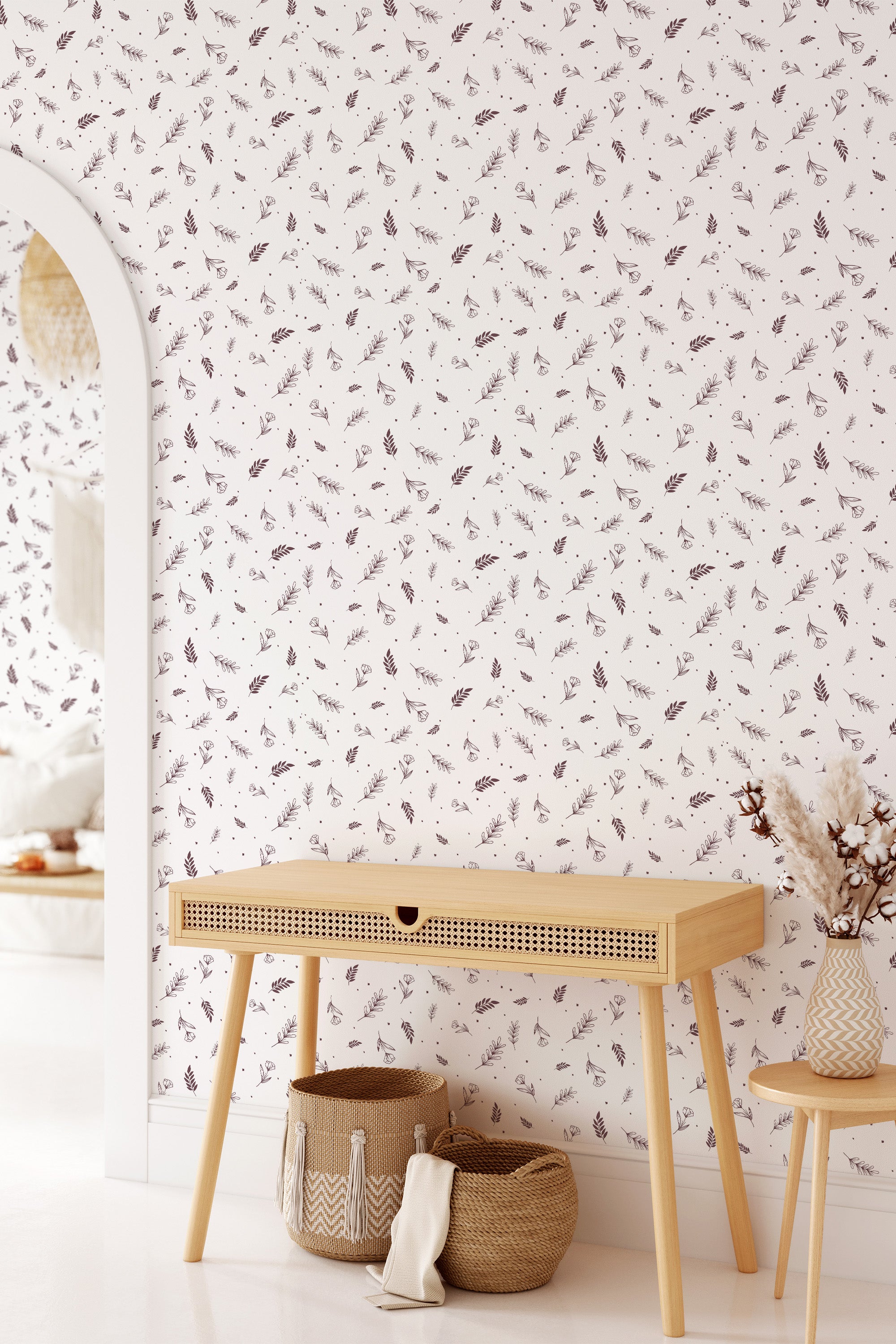 A room with a wall covered in floral print wallpaper, showcasing delicate flowers and botanical elements on a light background. Accentuated by wooden furniture and wicker baskets, the design reflects a soft and harmonious ambiance of traditional wallpaper.