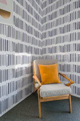 A room with wallpaper covering the walls, showcasing a pattern of purple brushstroke lines arranged vertically and evenly spaced. The design adds a modern yet classic touch to the space, creating a visually interesting and textured effect. The wallpaper is traditional wallpaper.