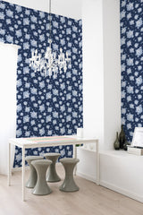 Dark blue wallpaper with a repeating pattern of white floral motifs covering the walls in a contemporary room, embodying the elegance of traditional wallpaper.