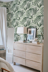 A room with walls covered in Green tropical leaf wallpaper showcasing large, lush, green leaves against a light background. Traditional wallpaper.