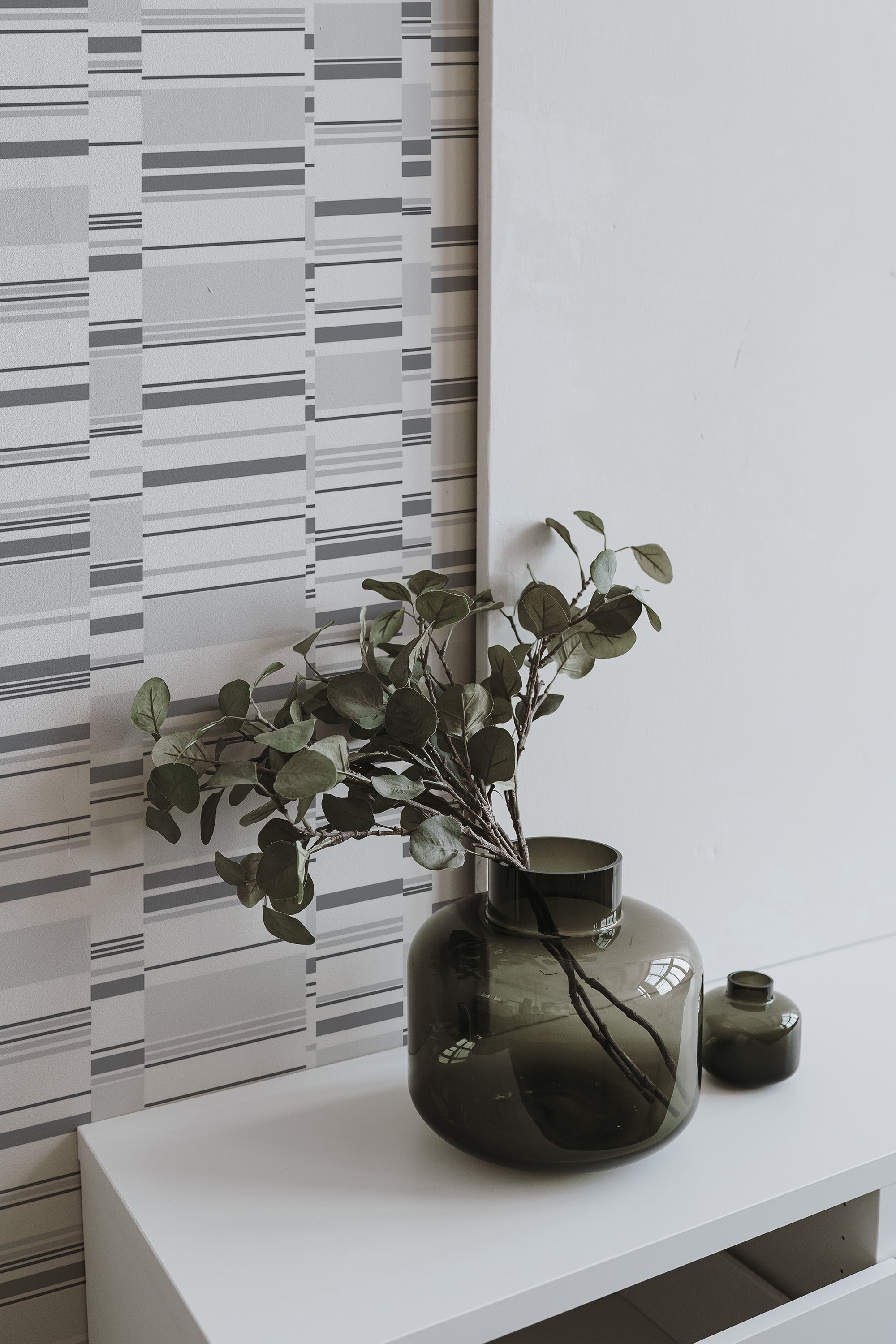 Self-adhesive wallpaper with a gray abstract stripes design, adding a modern touch with a geometric pattern of varying line thicknesses.