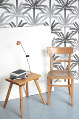 Self-adhesive gray and black palm tree wallpaper in a tropical pattern, creating a tranquil ambiance in the room with a blend of minimalist and natural elements.