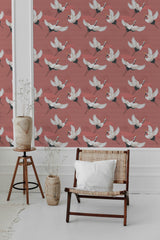 Wallpaper with a bird pattern in white and black with red accents across a muted red background. The birds are shown in flight with outstretched wings. Traditional wallpaper.