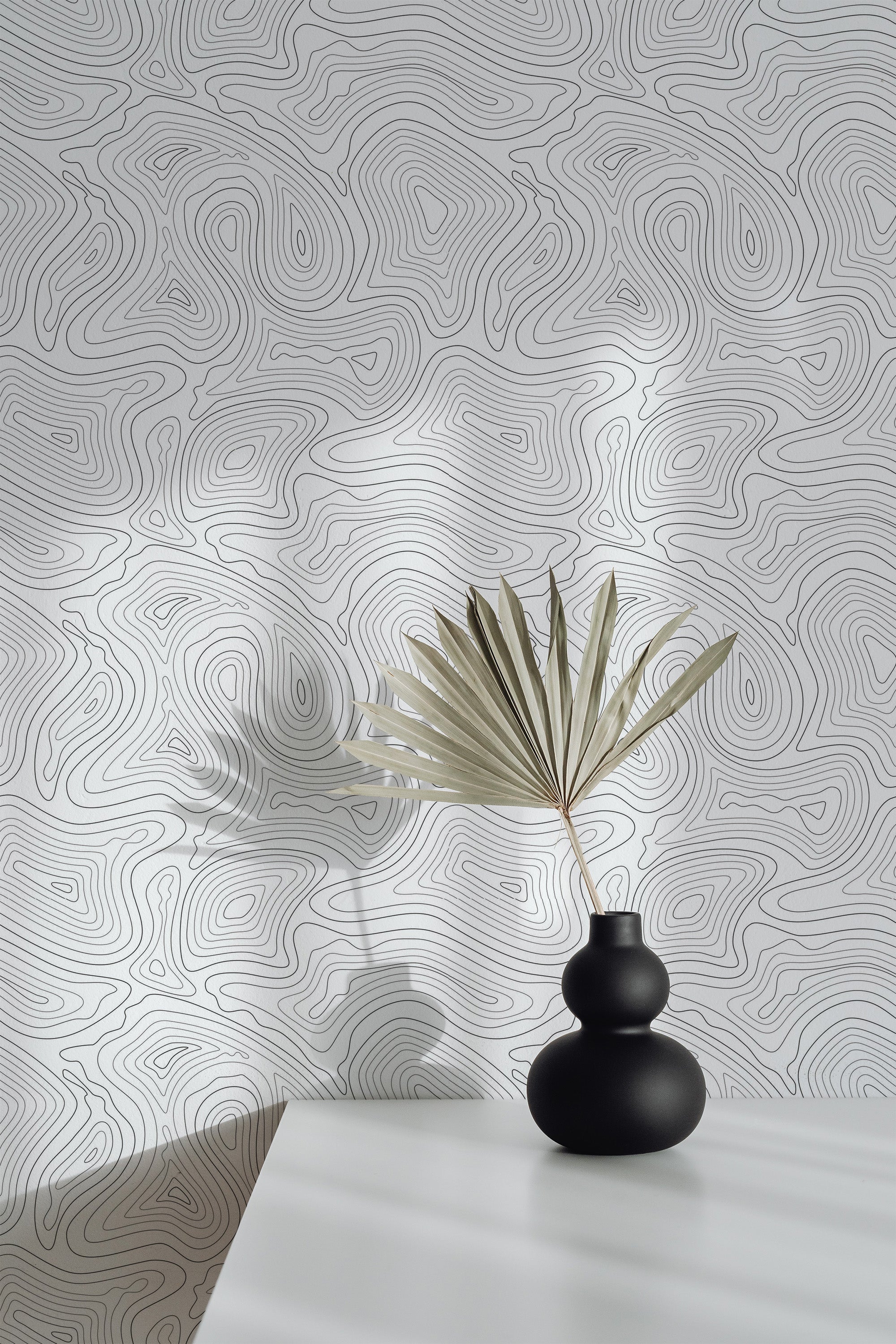 Self-adhesive wallpaper with an abstract tree line design, featuring continuous flowing lines resembling topographic maps in subtle shades of gray, creating a calming, modern aesthetic.