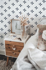 Self-adhesive wallpaper with a blue geometric floral pattern, creating a repetitive and uniform design on a white background in a cozy bedroom setting.