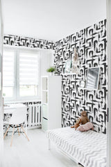 Black and white brushstroke lines cover the walls of a modern room, creating an abstract, artistic pattern on traditional wallpaper.
