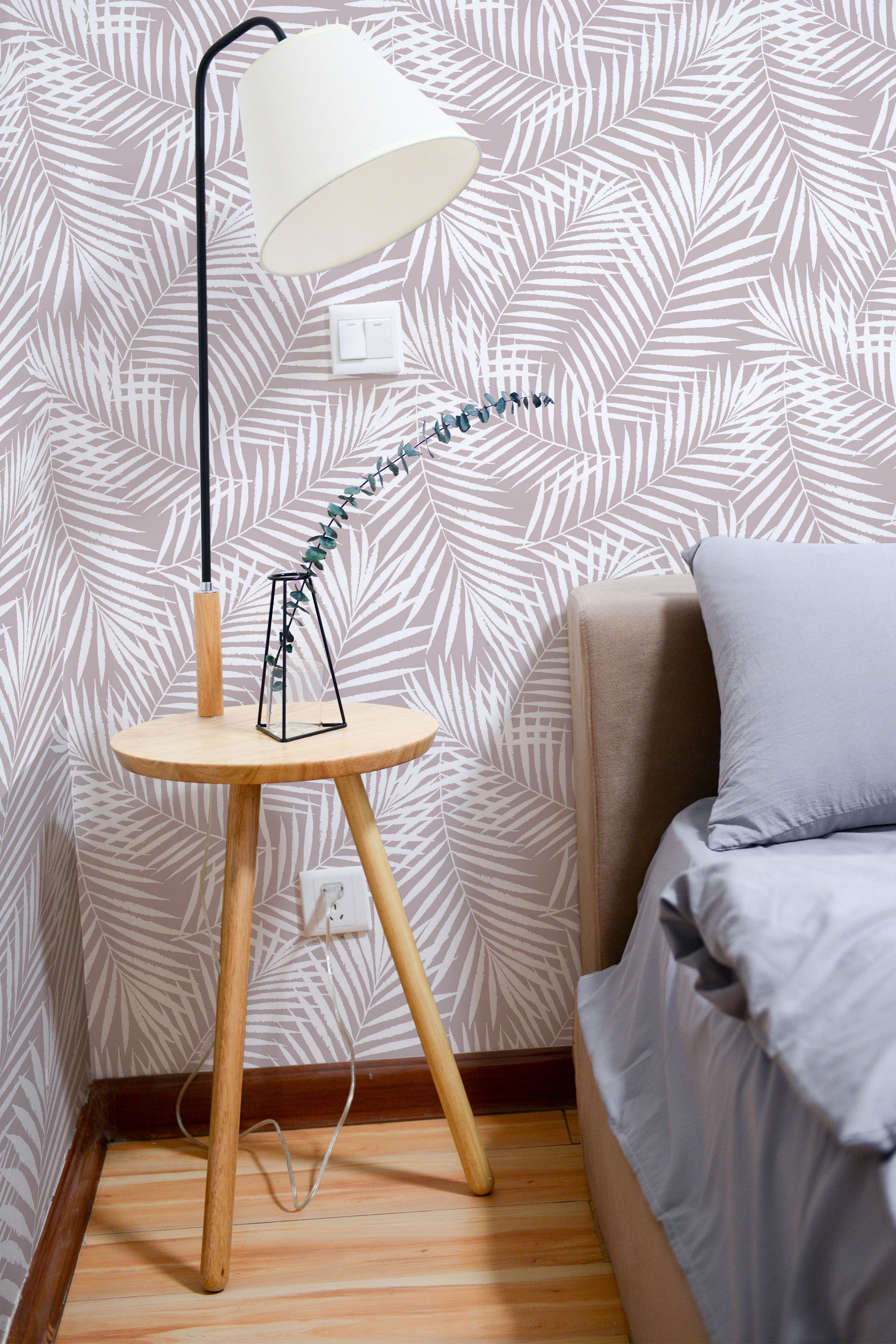 Self-adhesive jungle palm leaf wallpaper with a beige and white color scheme on a room wall, complementing the wooden floor and furniture.