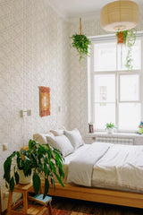 A room with Geometric art deco wallpaper with interlocking lines and shapes in a monochrome scheme on one wall, complementing the serene bedroom setup, with hanging plants and wooden furniture, categorized as traditional wallpaper.
