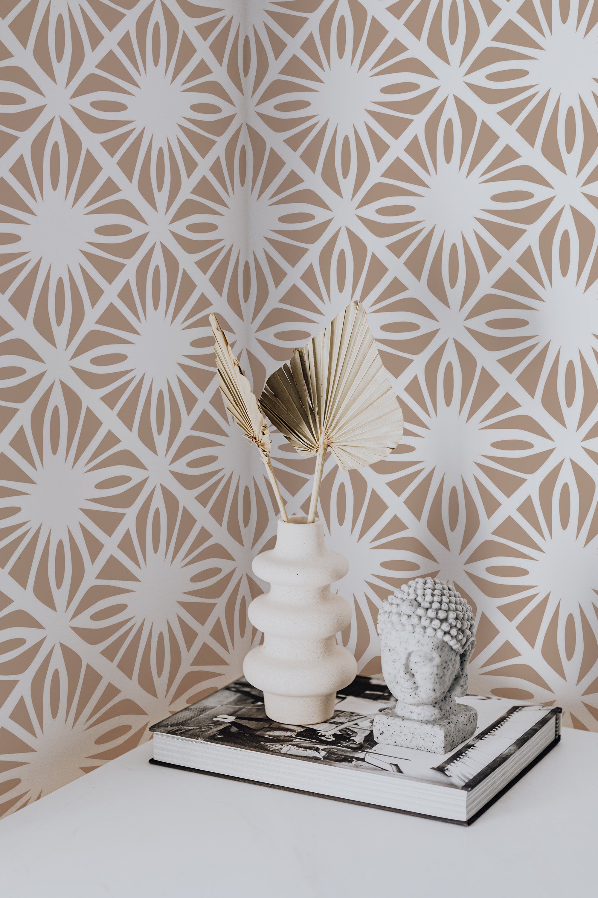Self-adhesive Moroccan tile pattern wallpaper with interlocking geometric shapes in neutral tones, accentuated by a decorative vase and book on a table.