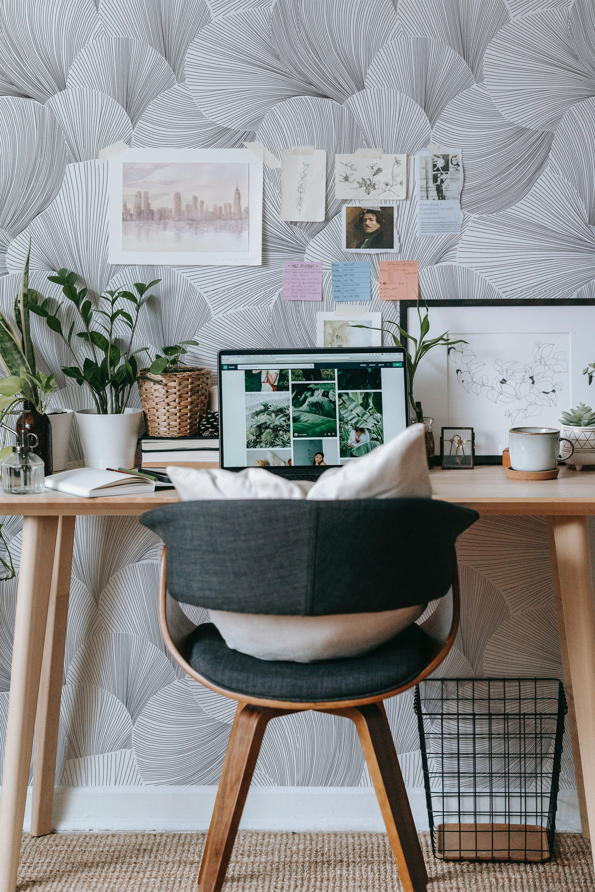 Self-adhesive wallpaper with a monochromatic seamless line art pattern, adorning the wall behind a workspace with a wooden desk, chair, and decorative plants.