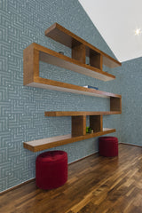 A room with walls covered in a geometric seamless square patterned wallpaper in blue and gray tones, complemented by wooden shelves and red stools, embodying a traditional wallpaper style.