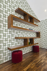 A room with Simple retro flower wallpaper pattern of stylized white flowers on a green background, with wooden shelving and red stools, traditional wallpaper.